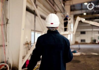 Stavebný dozor s prilbou sleduje práce na veľkej priemyselnej stavbe.