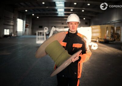 Pracovník v priemyselnom prostredí drží rolku izolačného materiálu, pripravený na montáž alebo inšta.