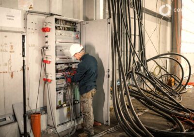 Elektrikár pri práci na rozvádzači s káblami v priemyselnom objekte.